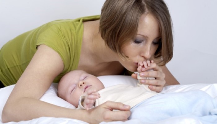 Maman qui embrasse son bébé en train de dormir