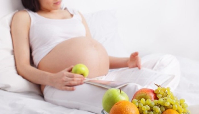 Femme enceinte qui va manger un fruit en lisant