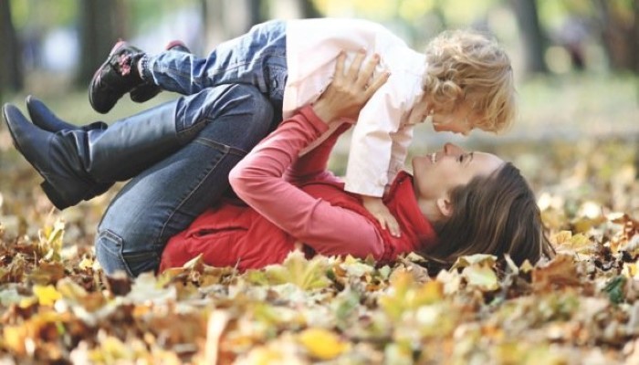 Maman et son enfant qui joue dans les feuilles