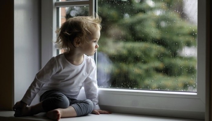 Petite fille assise sur le rebord d'une fenêtre Petite fille assise sur le rebord d'une fenêtre