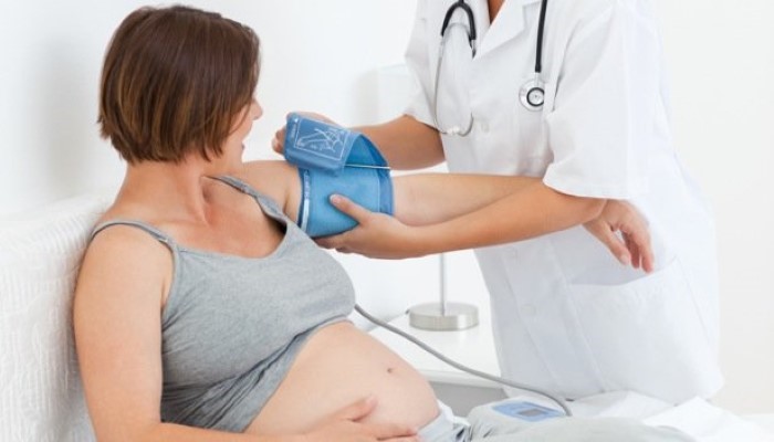 Infirmière mesurant la pression d'une femme enceinte Infirmière mesurant la pression d'une femme enceinte