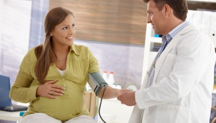 Un docteur prend sa tension à une femme enceinte