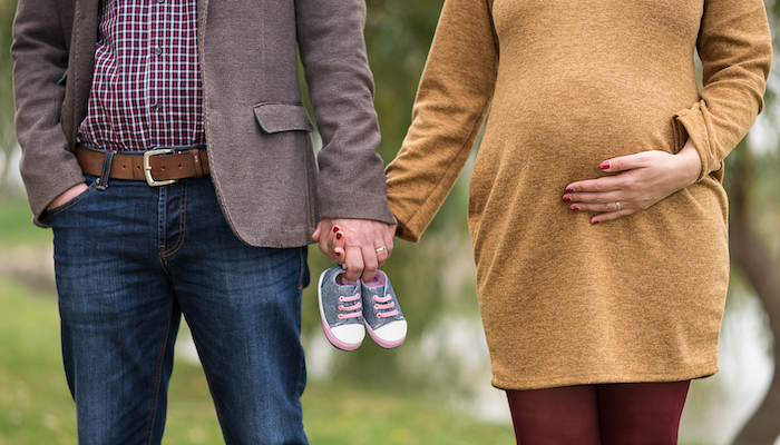 Femme enceinte qui met des chaussons de bébé sur son ventre Femme enceinte qui met des chaussons de bébé sur son ventre