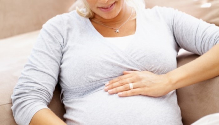 Femme enceinte assise dans le canapé Femme enceinte assise dans le canapé