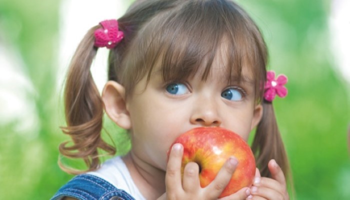 Petite fille qui mange une pomme