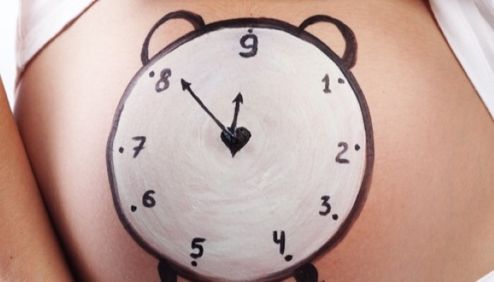 Réveil dessiné sur le ventre d'une femme enceinte