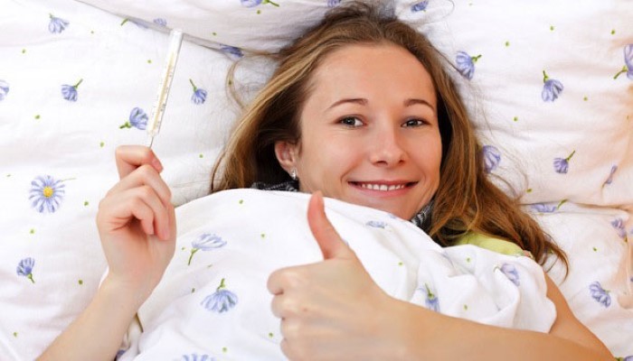 Femme qui vient de prendre sa température au saut du lit