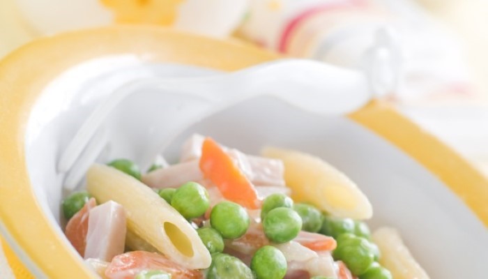 Assiette pour enfant avec des pâtes, des petits pois et des carottes