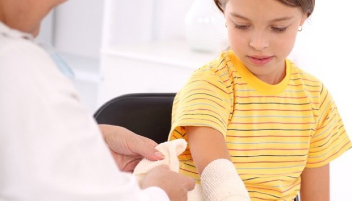 Enfant qui se fait bander l'avant-bras Enfant qui se fait bander l'avant-bras