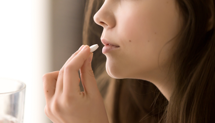 Jeune femme qui prend une gélule de médicament Jeune femme qui prend une gélule de médicament