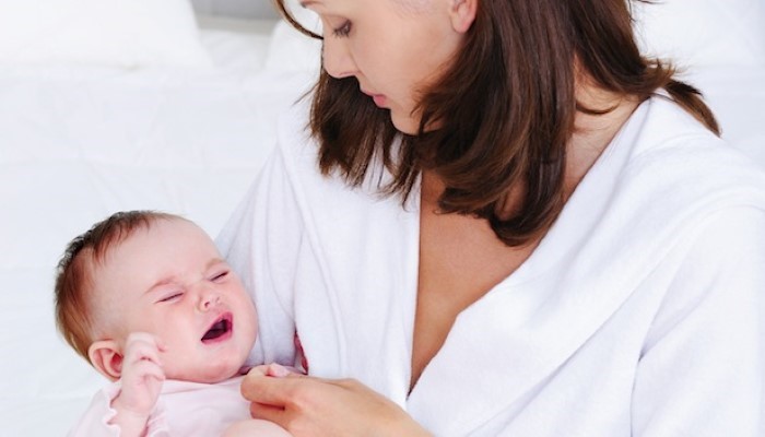 Bébé qui pleure dans les bras de sa maman