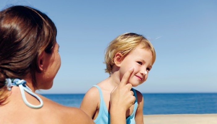 Maman qui met de la crème solaire à son enfant Maman qui met de la crème solaire à son enfant