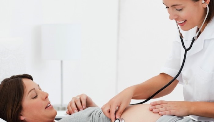 Sage-femme qui ausculte une femme enceinte Sage-femme qui ausculte une femme enceinte