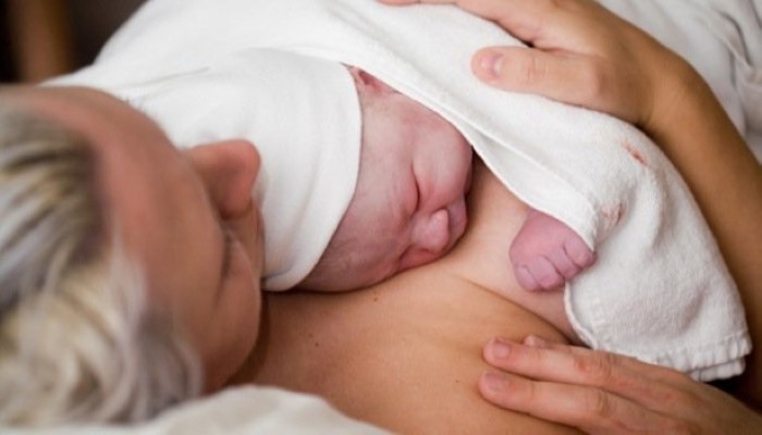 Maman qui tient son nouveau-né contre sa poitrine