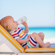Petit enfant qui boit un biberon d'eau en été Petit enfant qui boit un biberon d'eau en été