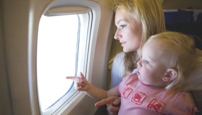 Bébé qui voyage en avion sur les genoux de sa maman Bébé qui voyage en avion sur les genoux de sa maman