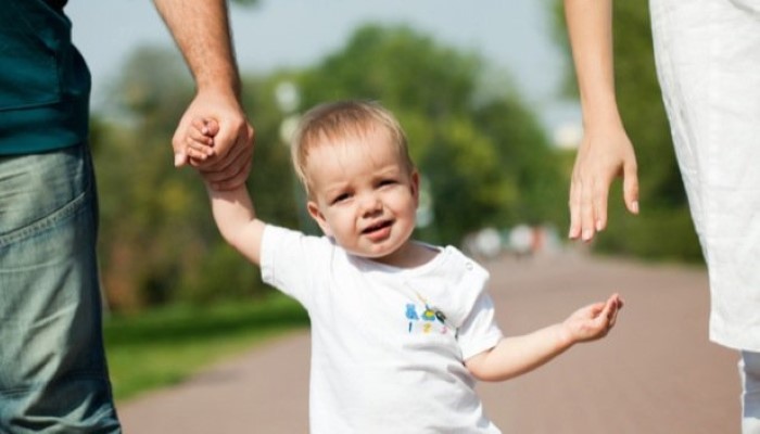 Bébé qui marche en donnant la main à papa et maman Bébé qui marche en donnant la main à papa et maman