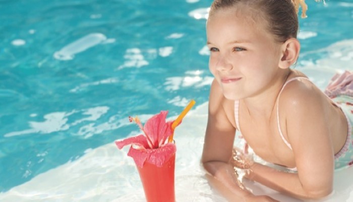 Petite fille au bord de la piscine avec un smoothie