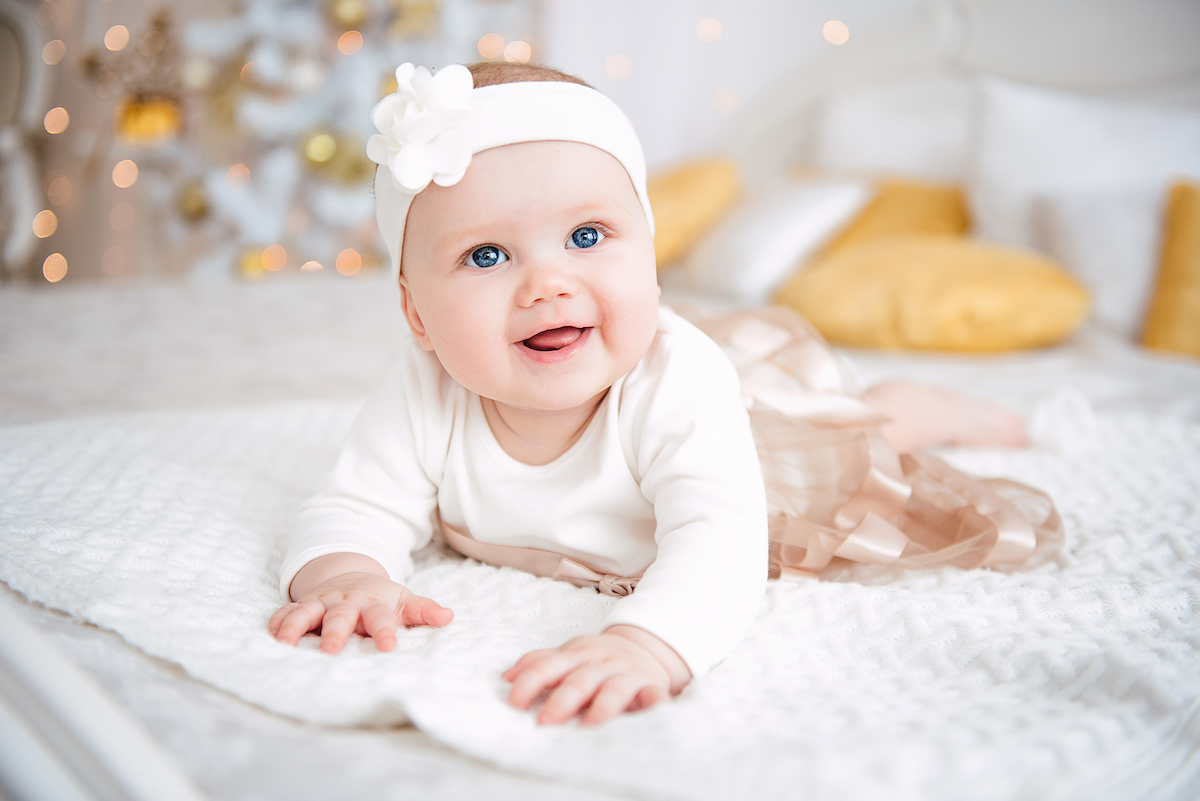 Petite fille qui sourit sur un lit de plumes roses