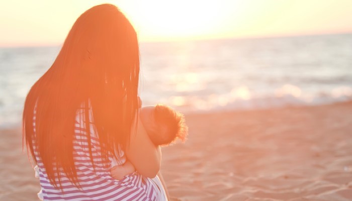 Maman de dos qui donne le sein à son enfant Maman de dos qui donne le sein à son enfant