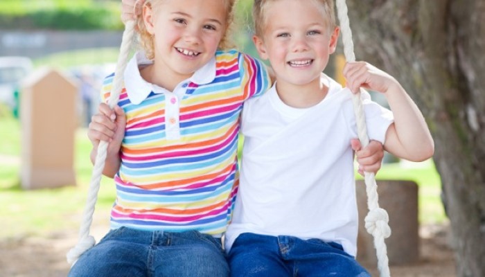 Petit garçon et petite fille assis sur une balançoire