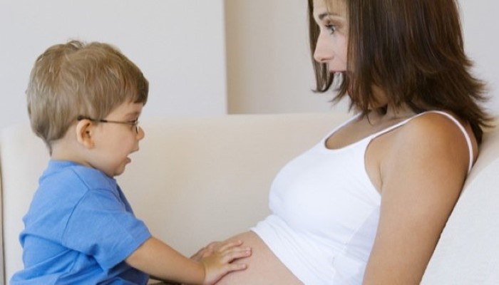 Petit garçon qui touche le ventre arrondi de sa maman Petit garçon qui touche le ventre arrondi de sa maman