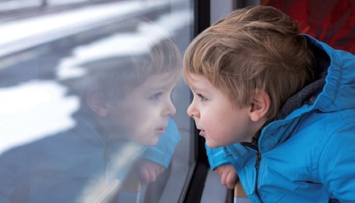 Petit garçon regardant par la fenêtre dans un train Petit garçon regardant par la fenêtre dans un train