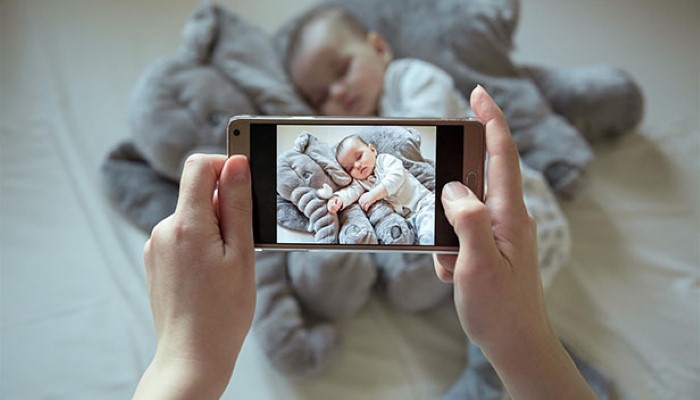 Une maman qui prend une photo de son bébé avec son smartphone Une maman qui prend une photo de son bébé avec son smartphone