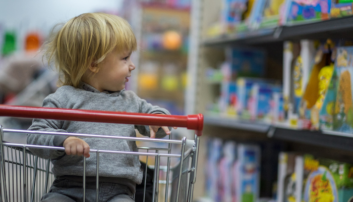Petit garçon assis sur le chariot d'un magasin Petit garçon assis sur le chariot d'un magasin
