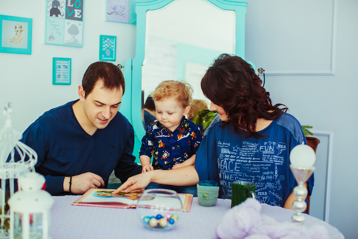 Un enfant qui regarde un livre avec ses parents Un enfant qui regarde un livre avec ses parents